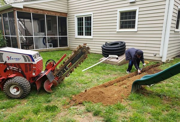 A man is digging a hole in the ground in front of a house.