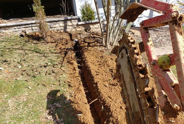 A machine is digging a trench in a yard