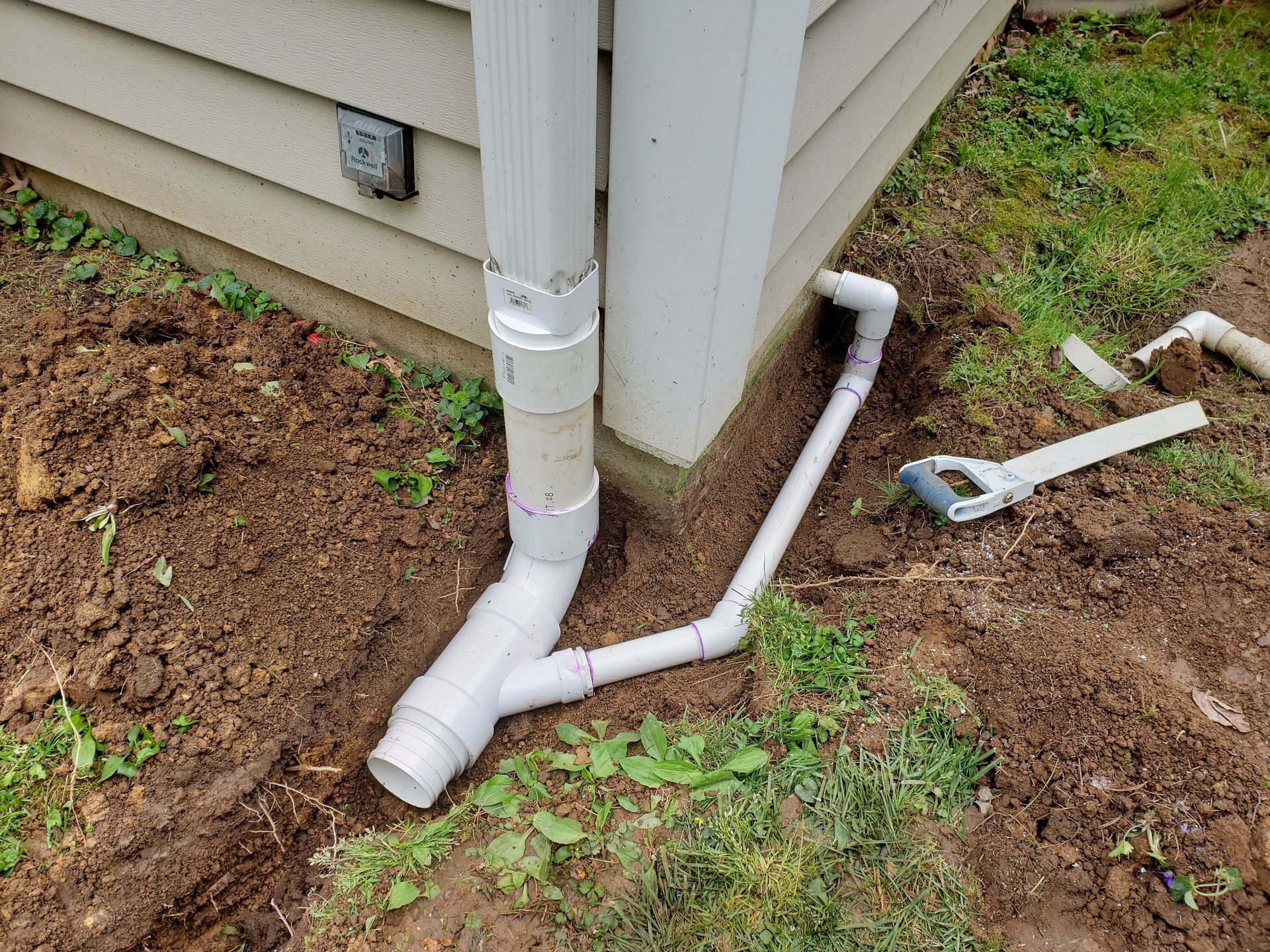 A drain pipe is being installed on the side of a house.