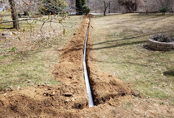 A pipe is being installed in the dirt in a yard.