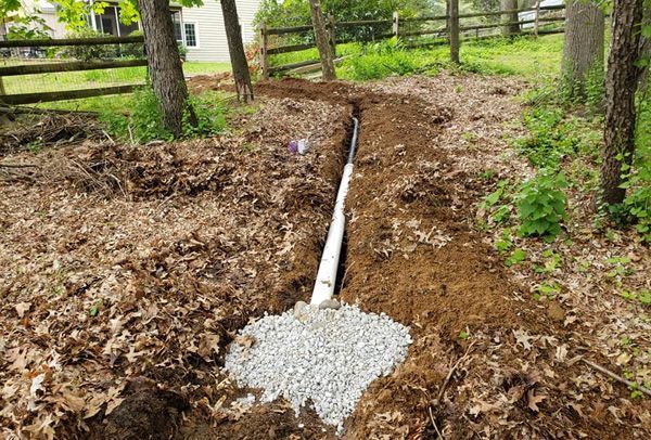 A pipe is being installed in the dirt in a yard.