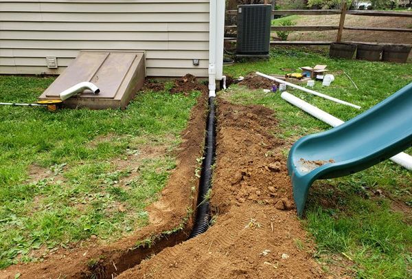 A green slide is being installed in a backyard.