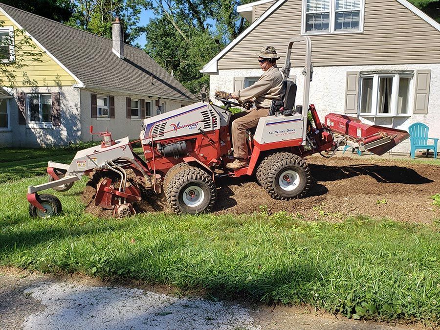 A man is riding a tractor in front of a house.