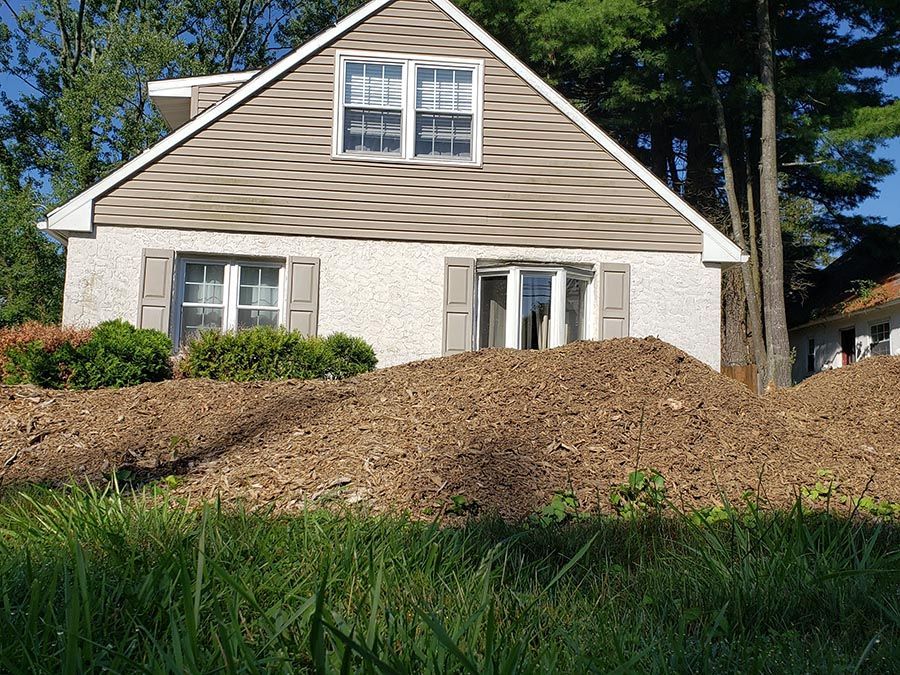 A house sits on top of a hill with a pile of dirt in front of it