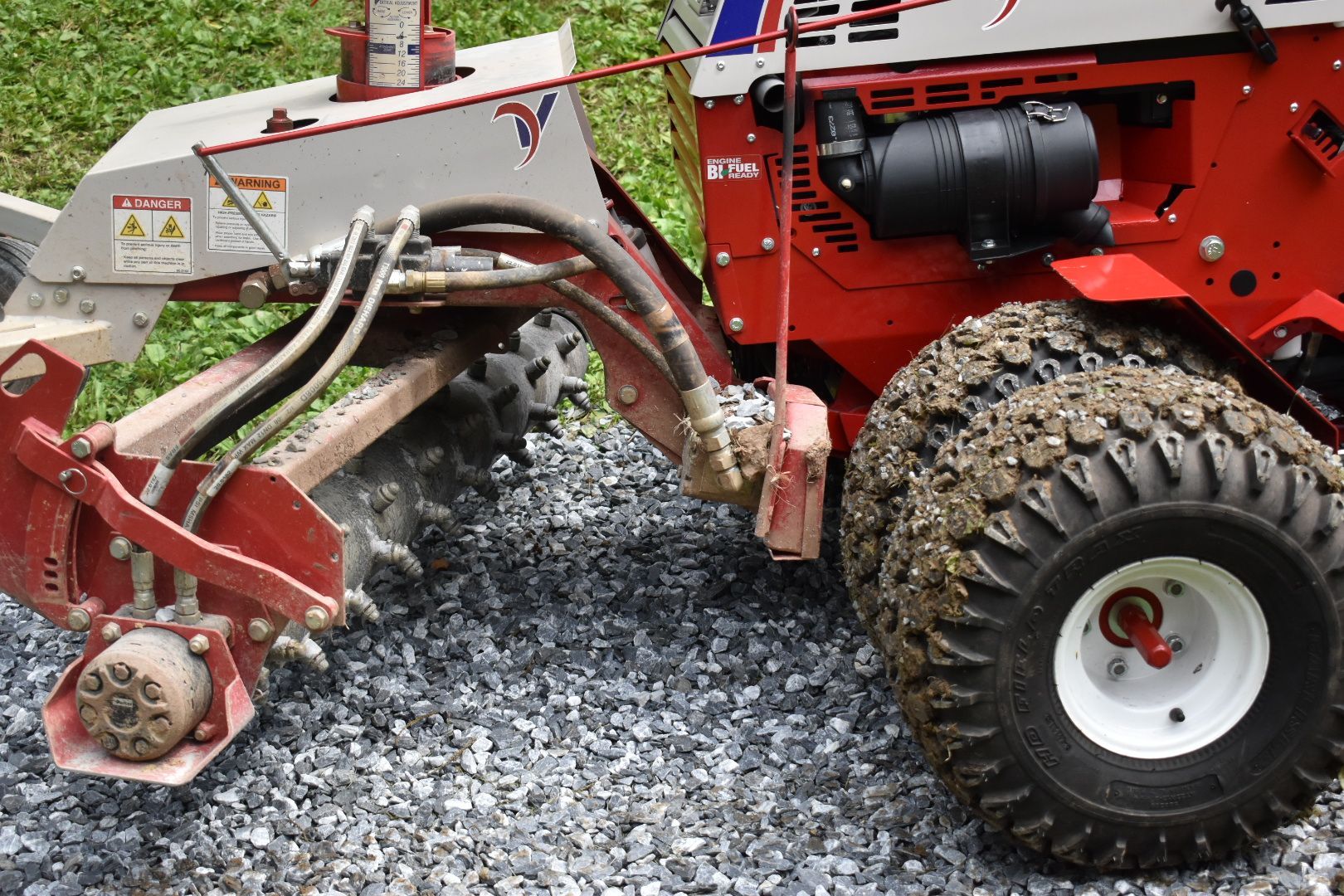 A red and white tractor is parked on gravel.