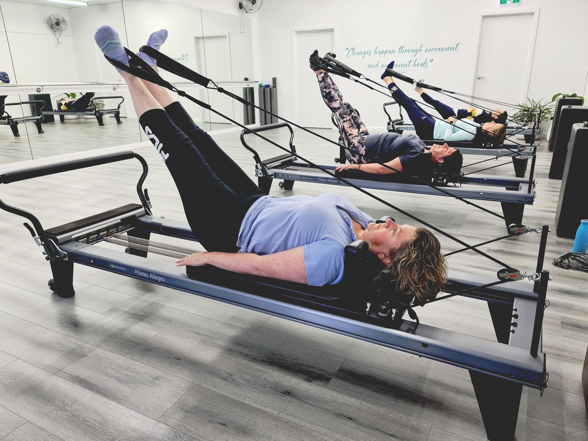 Reformer class of women stretching with a pilates reformer machine