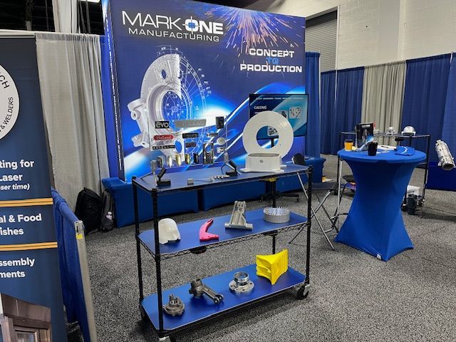 Trade show booth displaying manufacturing parts and a backdrop for