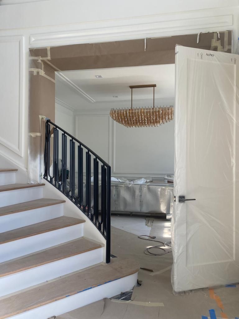 Interior doorway with open white door, staircase, and a partially furnished room with a chandelier