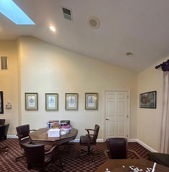 Small conference room with oval table, dark chairs, framed wall art, and sloped white ceiling with skylight.