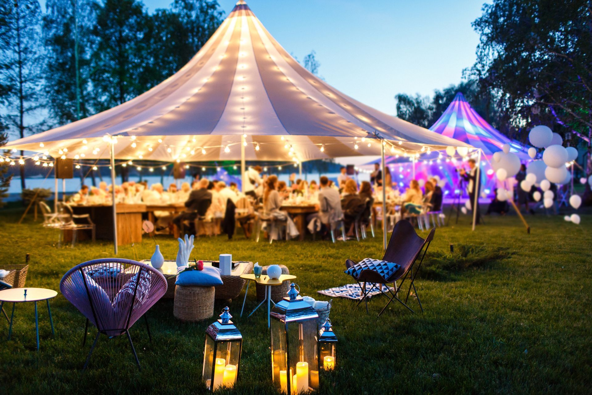 Outdoor evening party under a lit tent with guests
