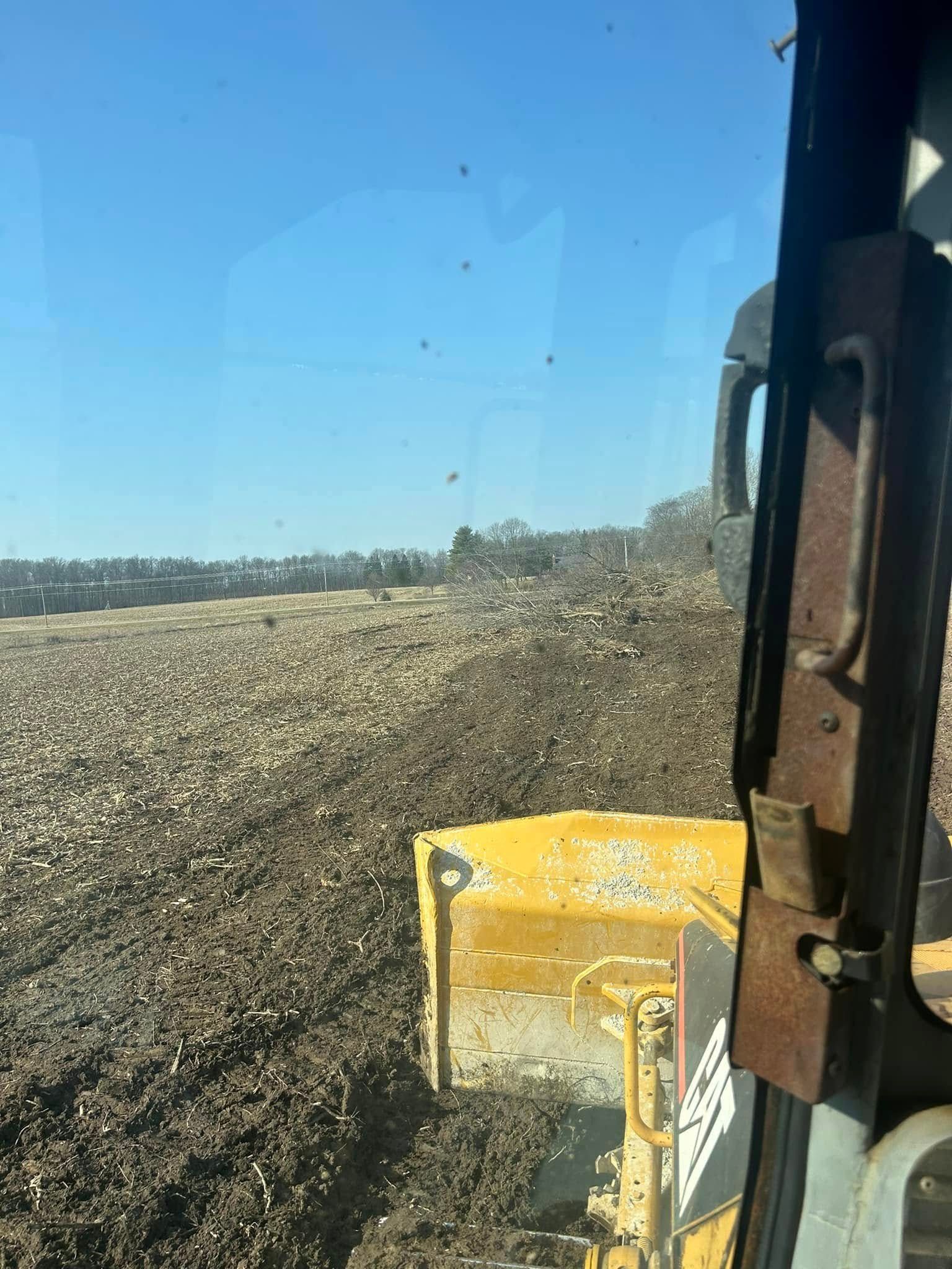 Bulldozer pushing dirt; blue sky.