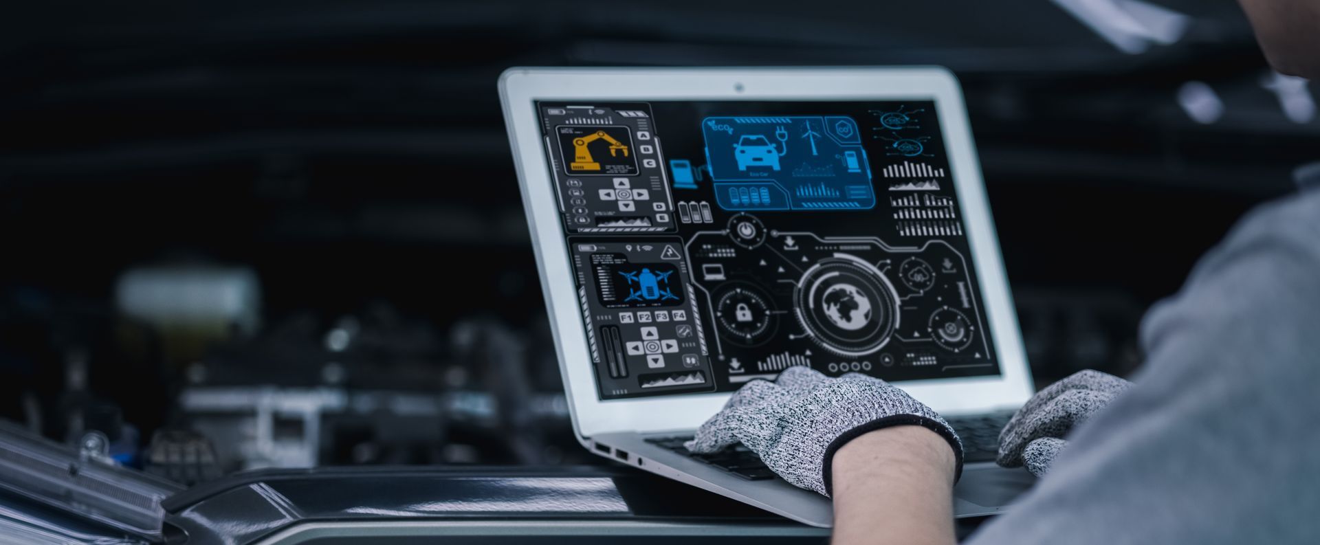 A mechanic using a laptop to diagnose a car engine, wearing gloves, and working in a garage.