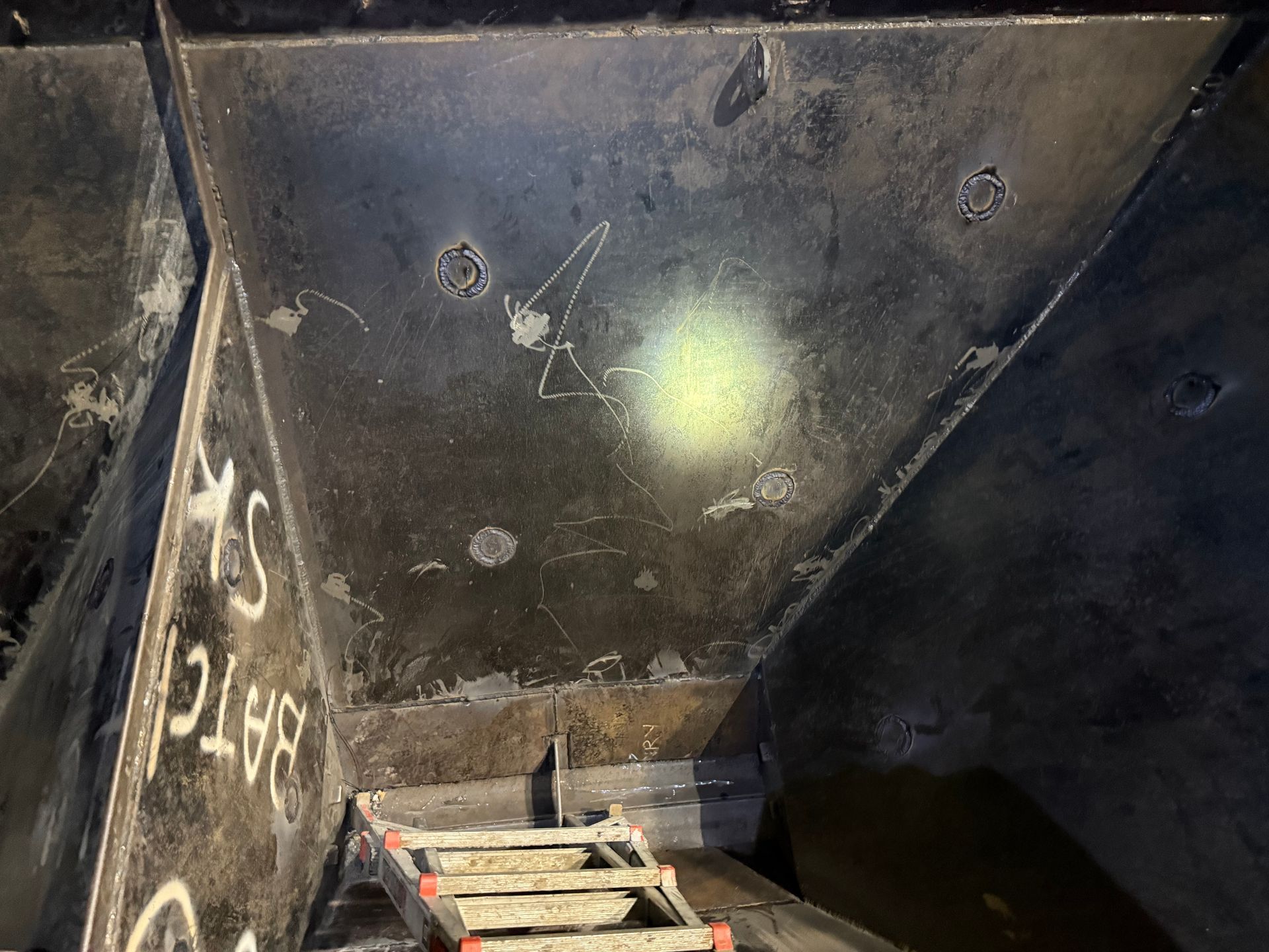 Dark Interior of a Metal Hopper With Graffiti and a Lit Spot — Lincoln Fabrication in Miles End, QLD