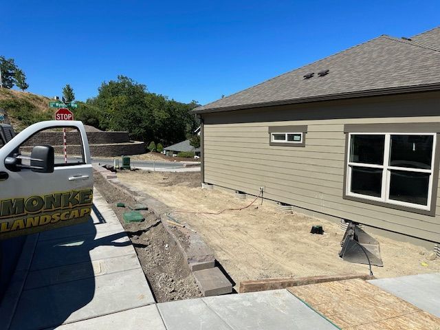 A tan house with new windows under construction next to a driveway and a parked landscaping truck on a sunny day.