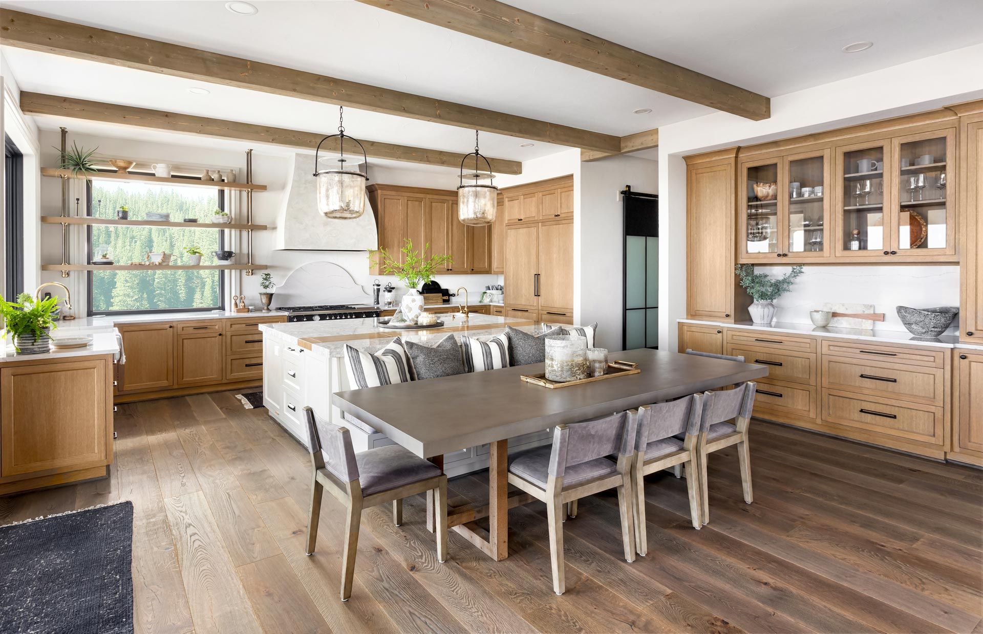 Bright kitchen and dining area with wood beams, white island, and wooden table and chairs