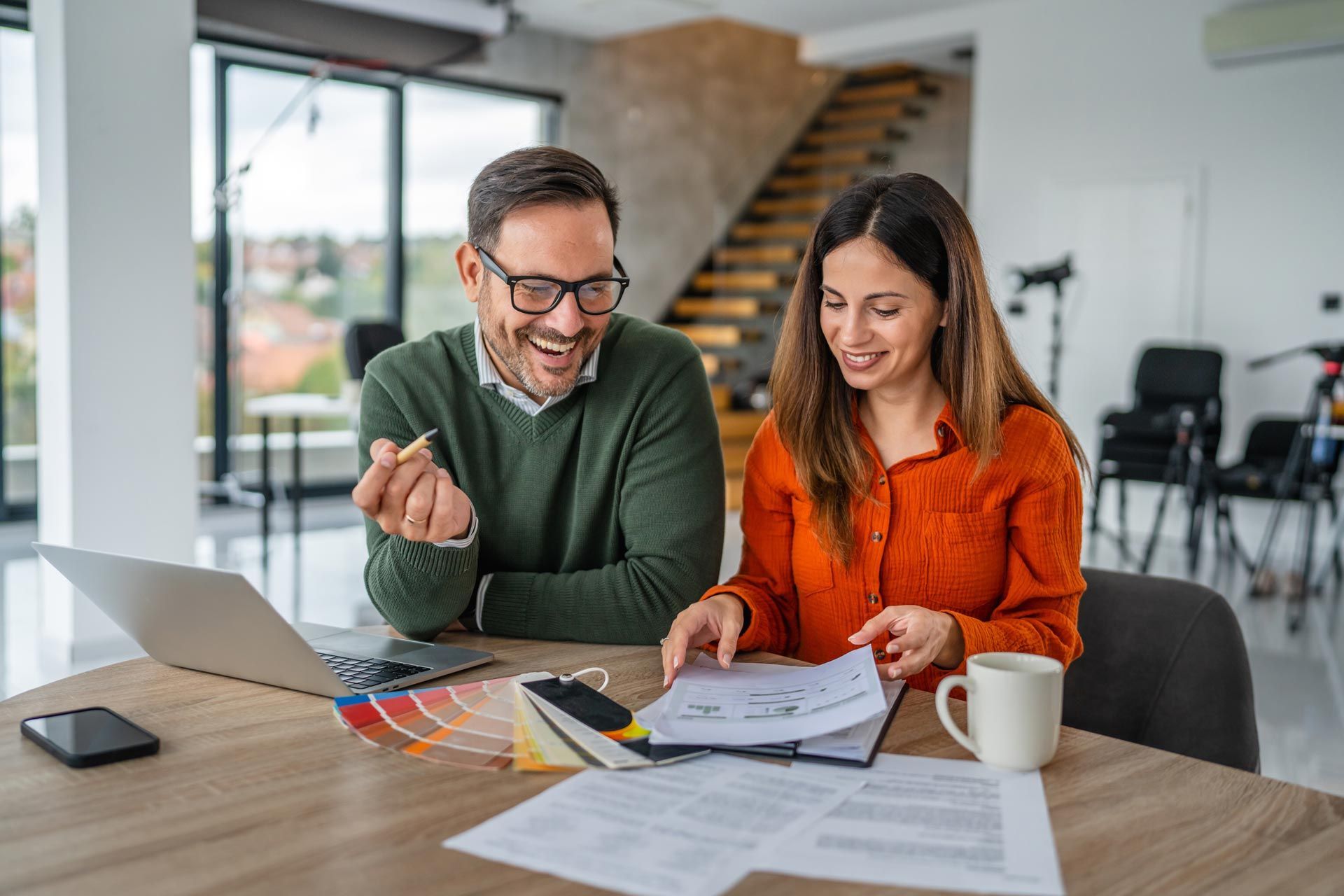 Two people reviewing documents and color swatches at a table in a bright office