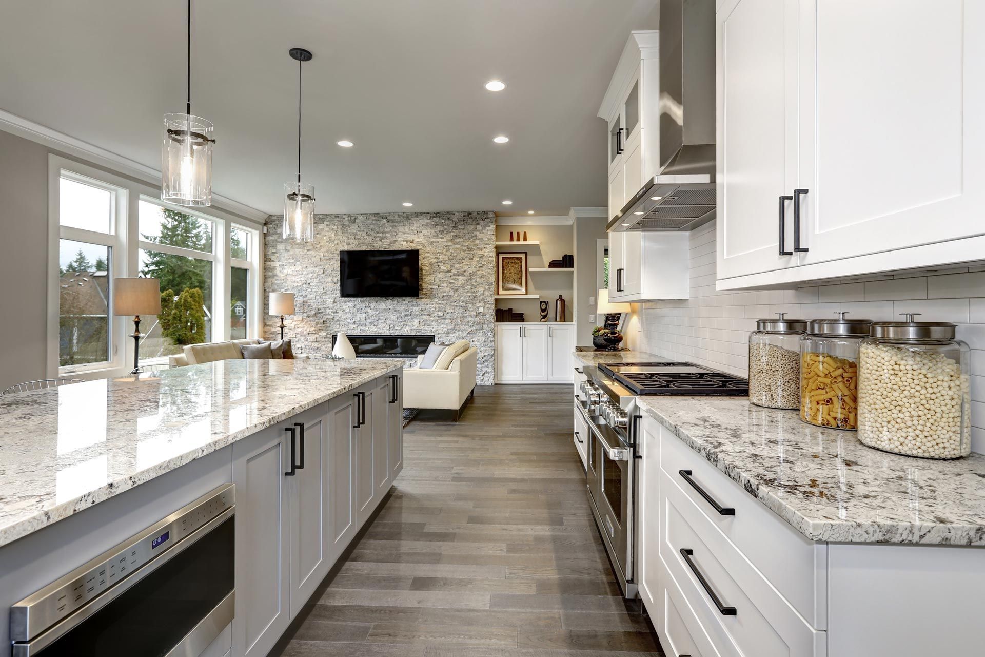 Modern white kitchen with granite counters, island seating, and stainless steel appliances