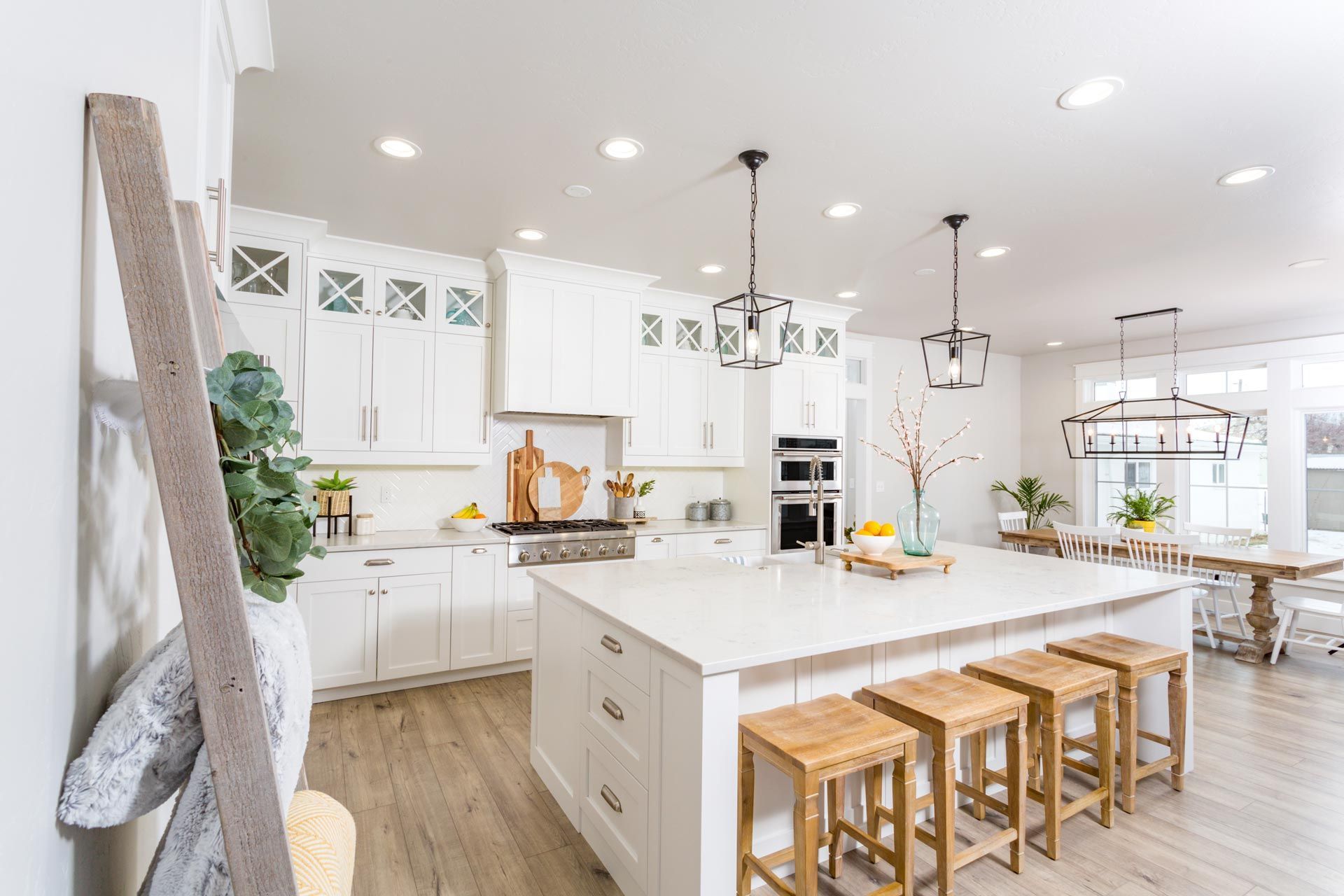 Bright white modern kitchen with island, wooden stools, and pendant lights