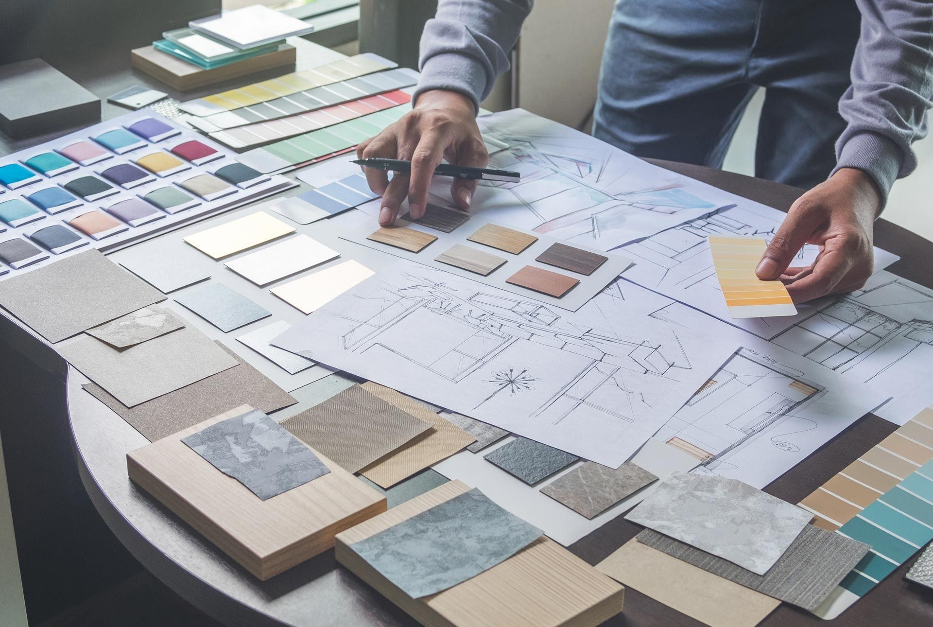 Hands arranging fabric and paper swatches on a design mood board workspace