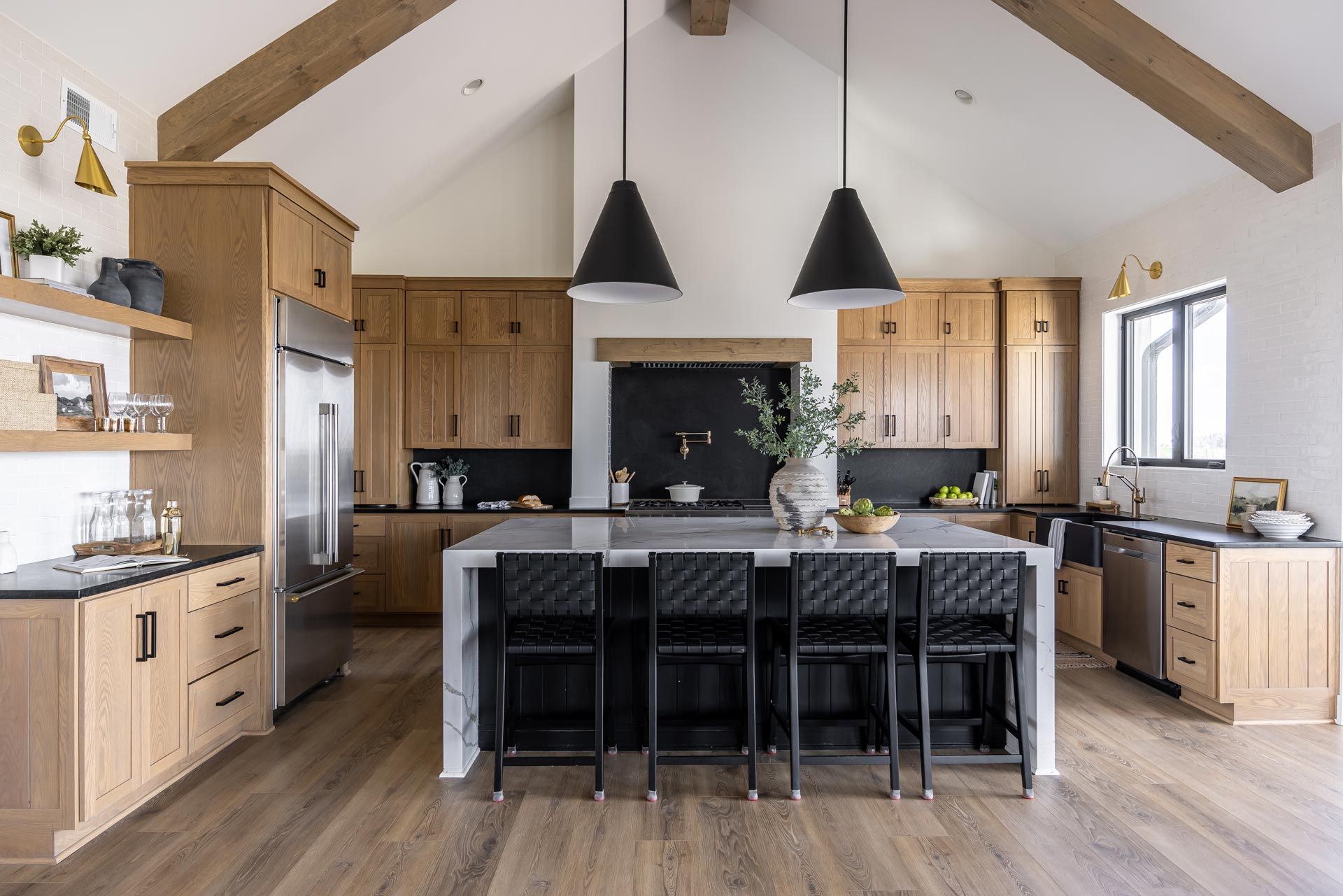Bright modern kitchen with wood cabinets, island seating, black pendants, and vaulted ceiling
