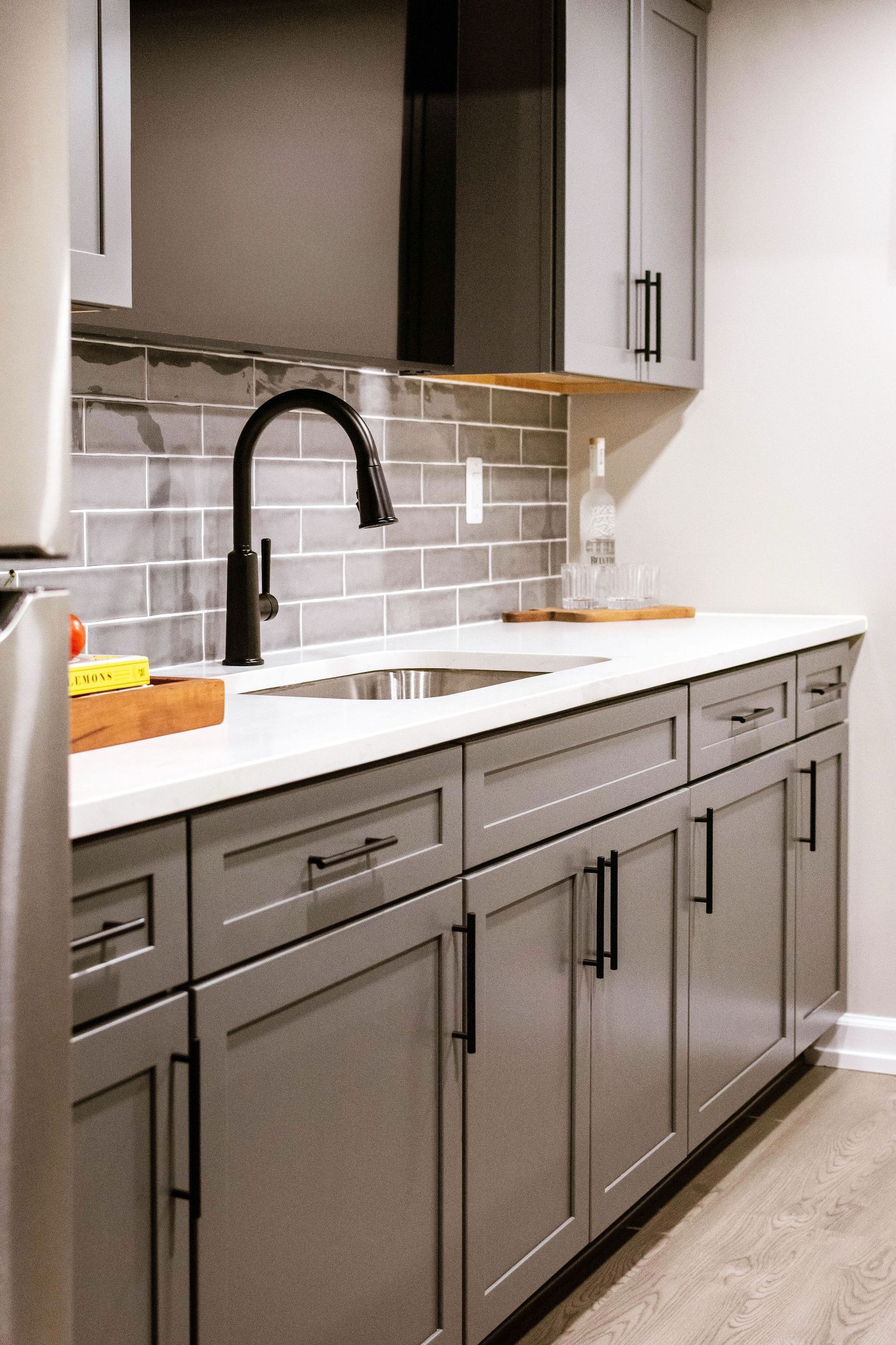 Modern kitchen with black cabinets, white island, pendant lights, and light wood floors