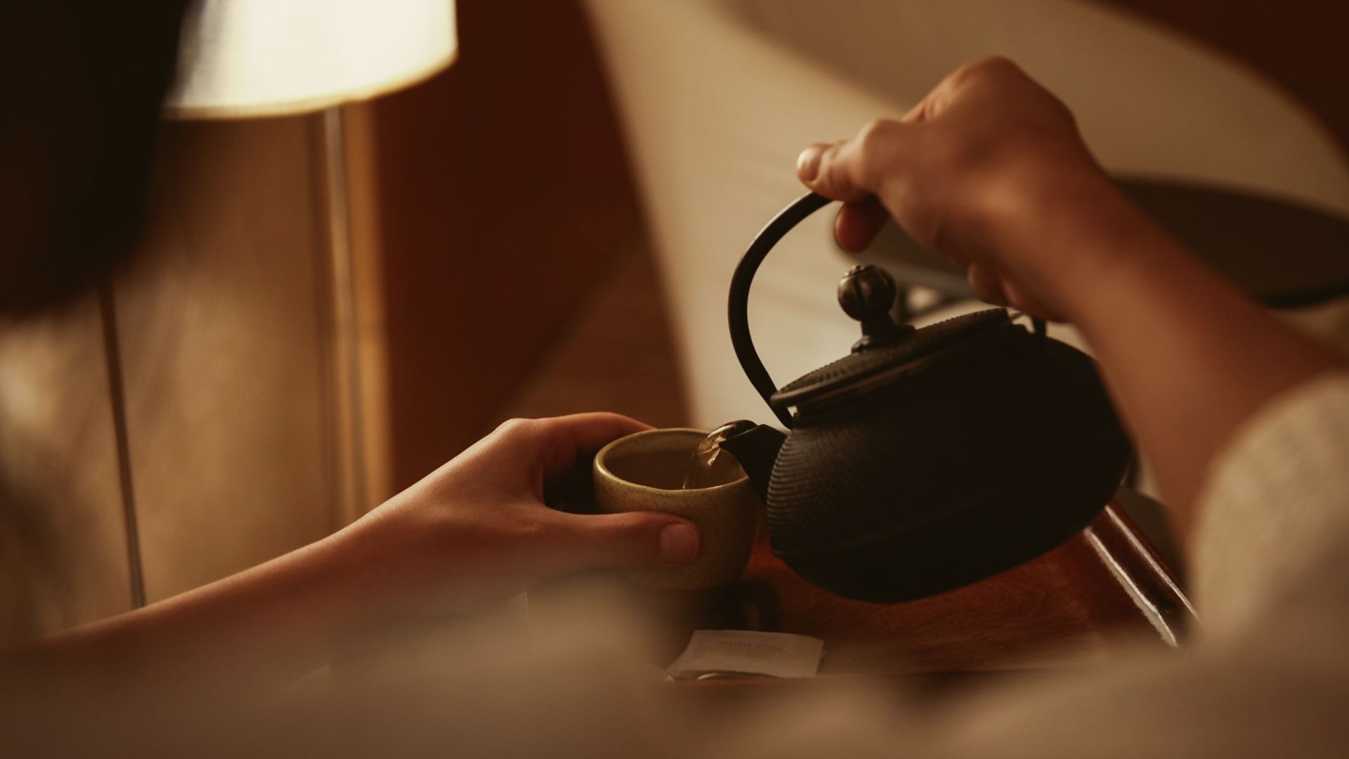 Una persona está sirviendo té en una taza de una tetera.