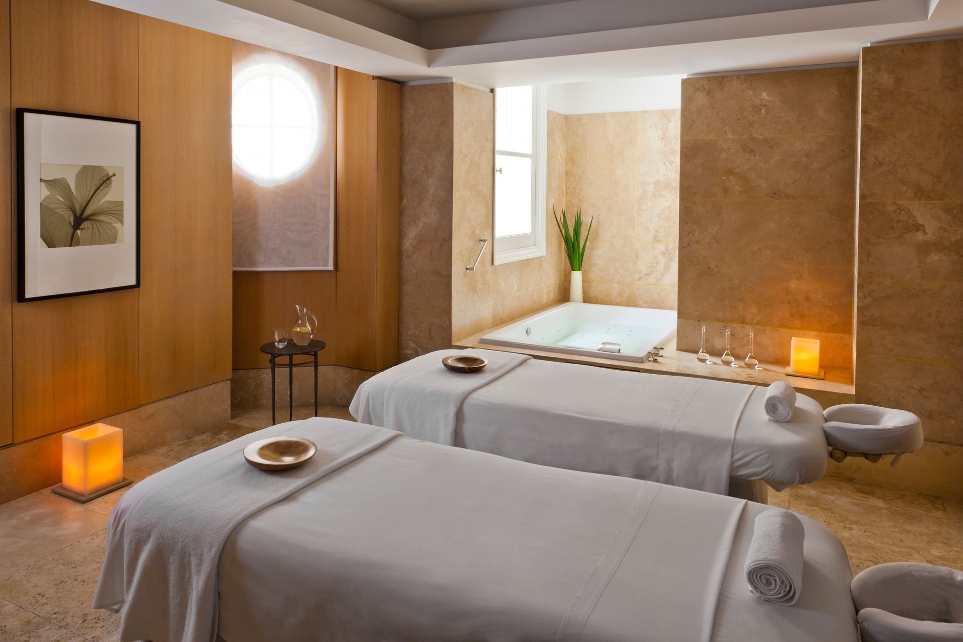 Dos mesas de masaje en un spa con una bañera al fondo.