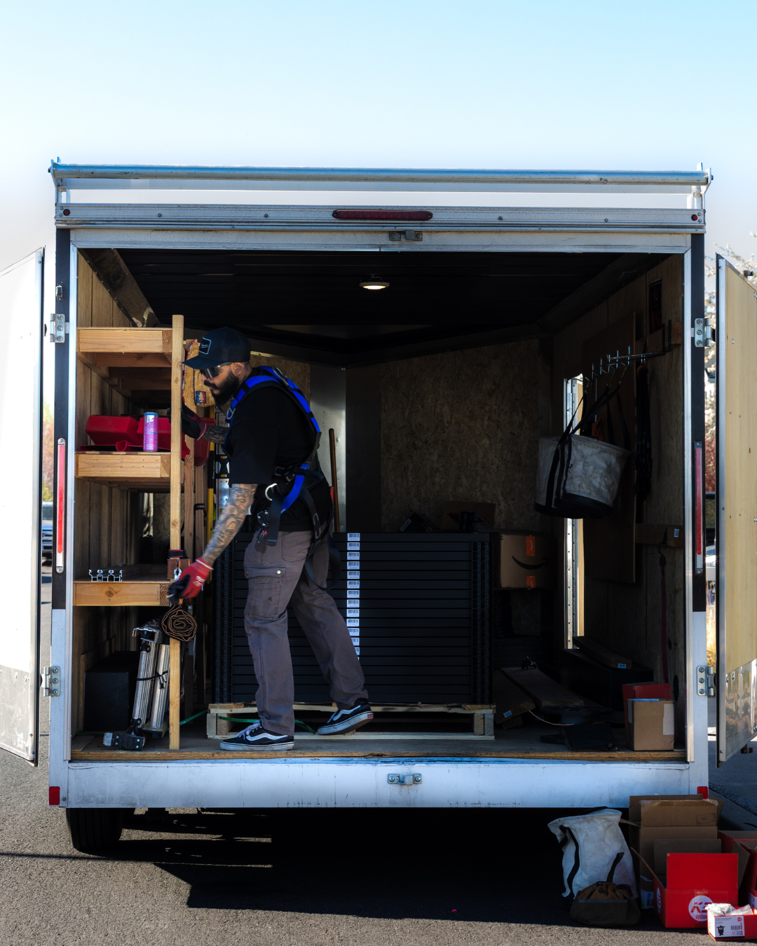 Person loading tools in the back of an open work trailer.