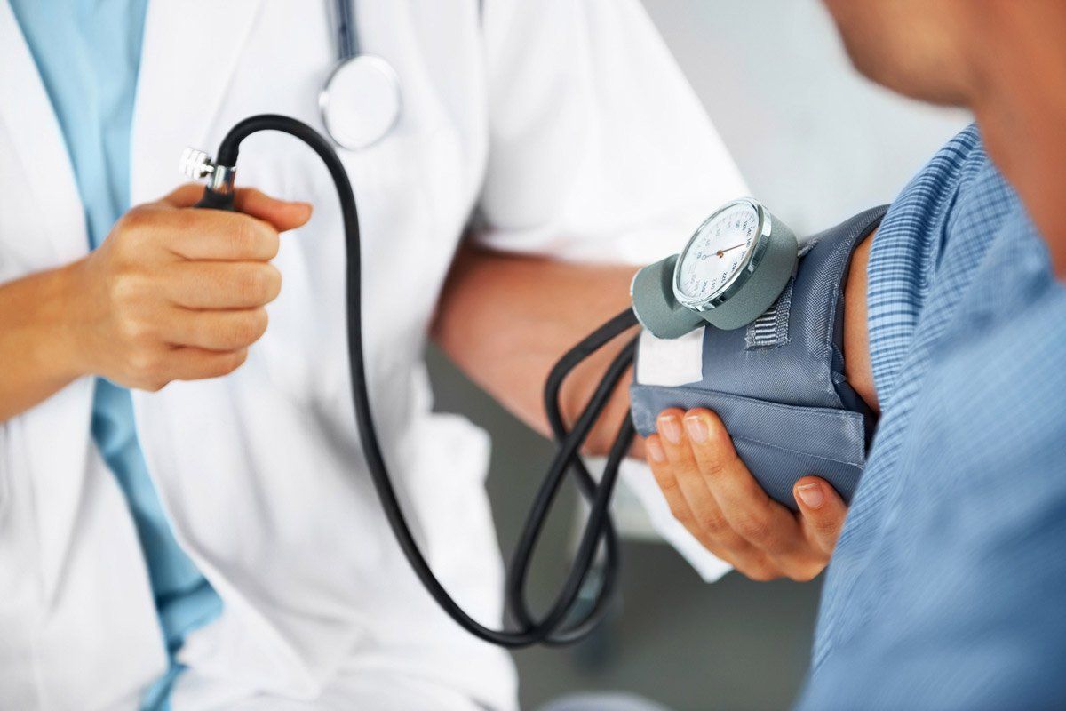 Doctor taking a patient's blood pressure with a stethoscope and cuff.