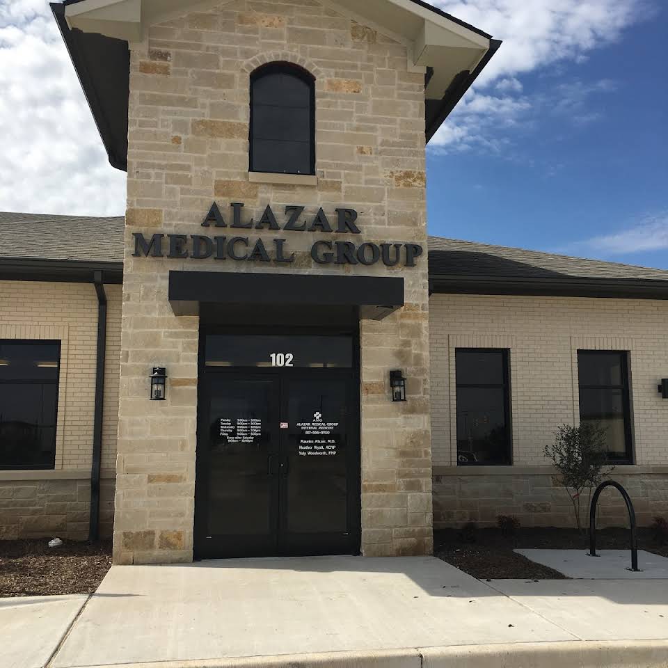Alazar Medical Group building with stone facade, black door and windows, under a blue sky.