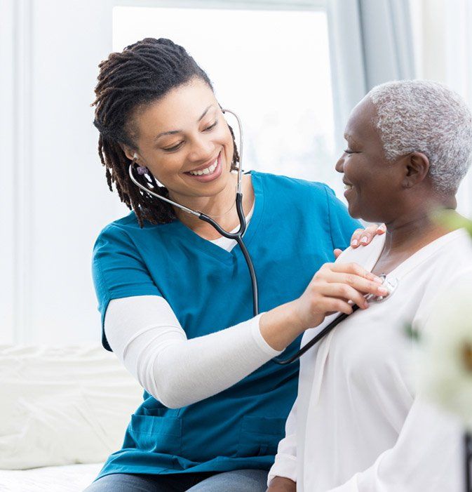 Nurse listening to patient's heart with stethoscope; both smiling, in a medical setting.