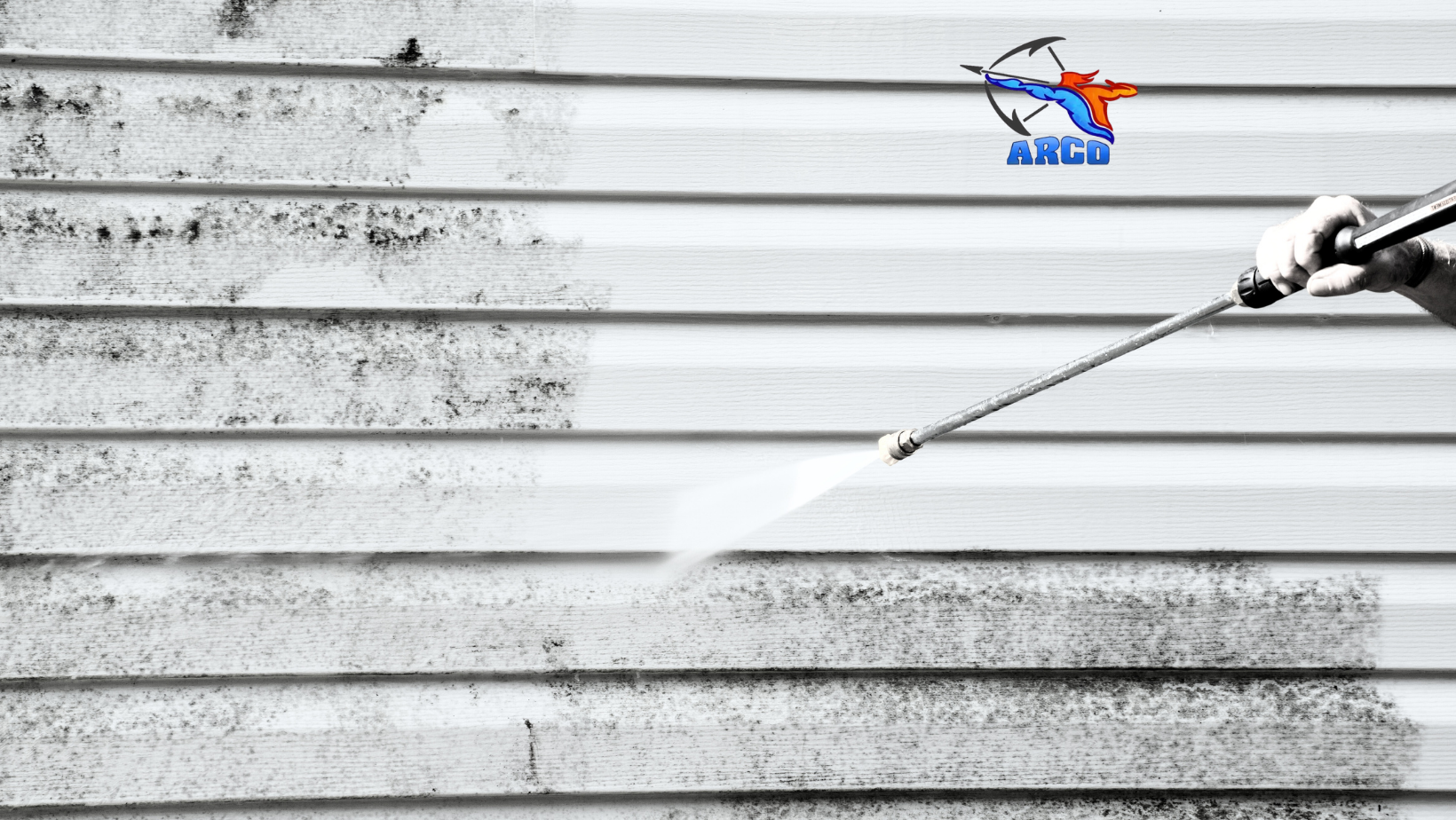 A person is cleaning siding on mobile home with a high pressure washer.
