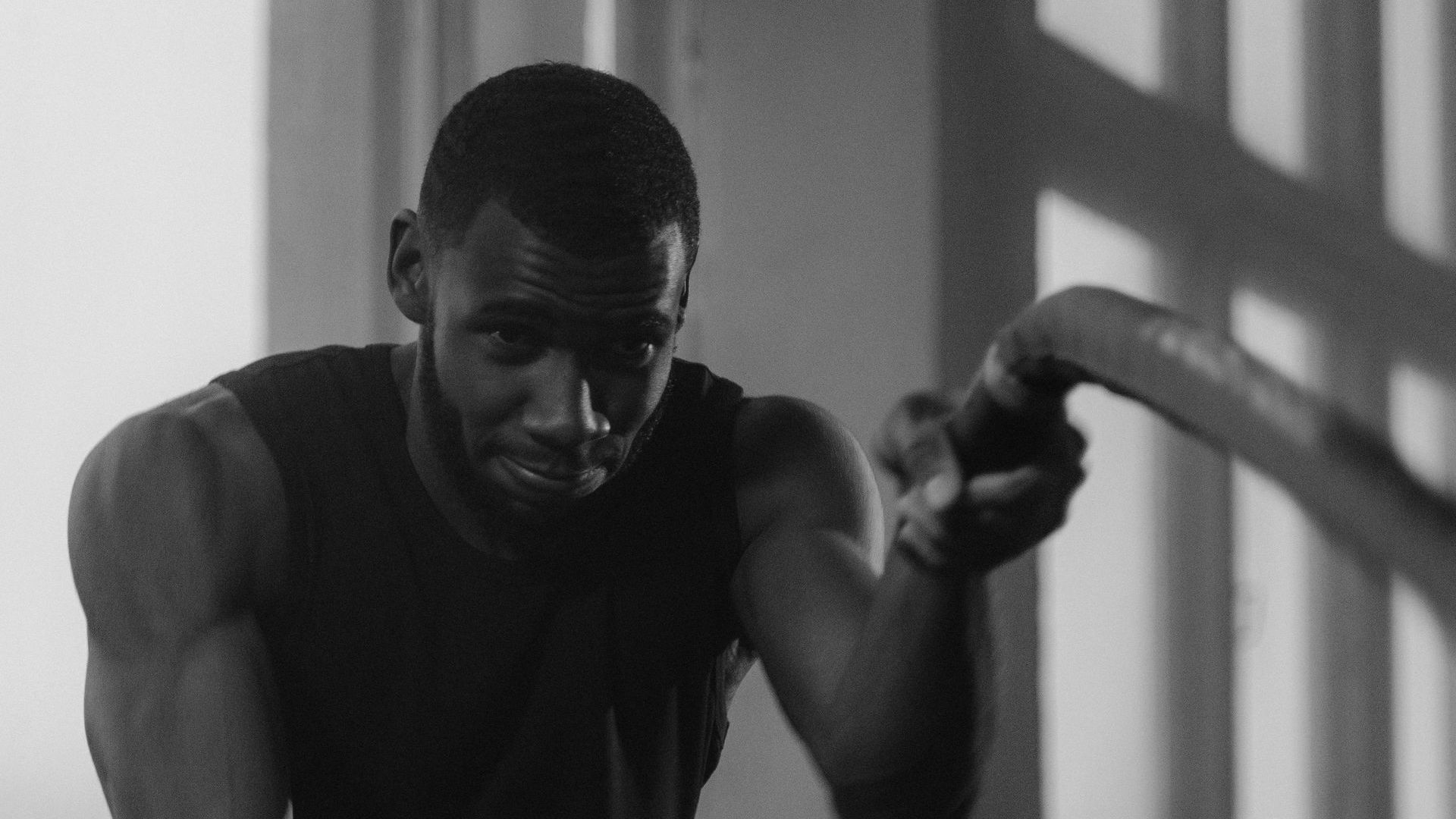 Man working out with battle ropes in gym, in black and white.
