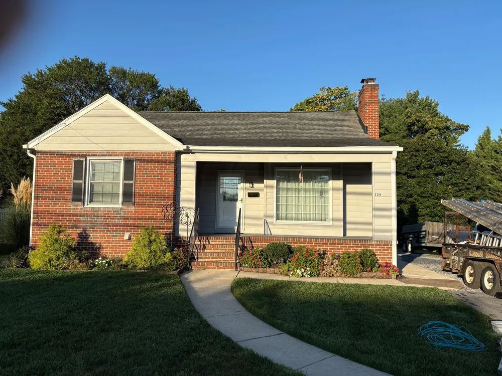 A single-story house with a brick facade on the left and light siding on the right, featuring a front porch and walkway.