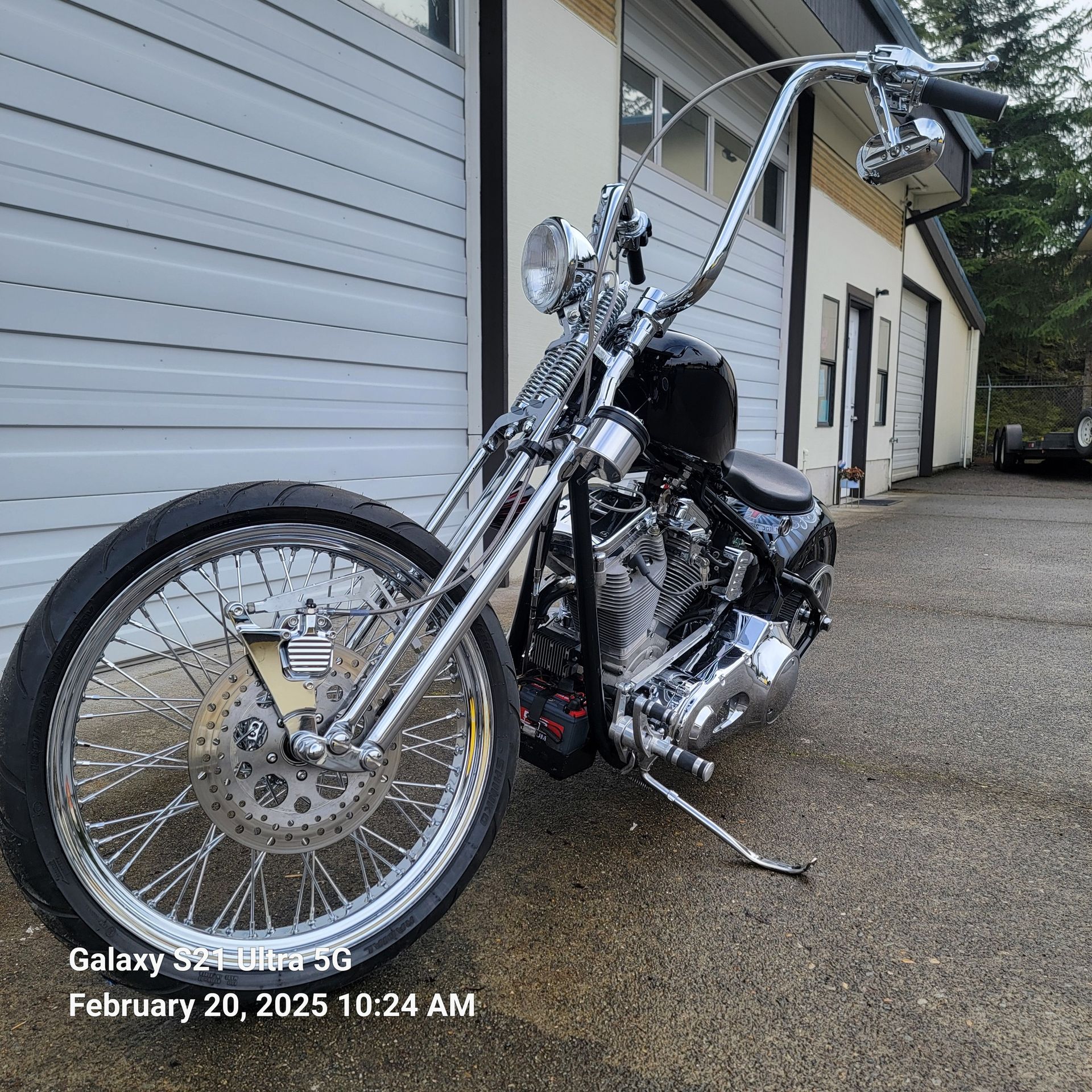 A chopper motorcycle is parked in front of a garage door.