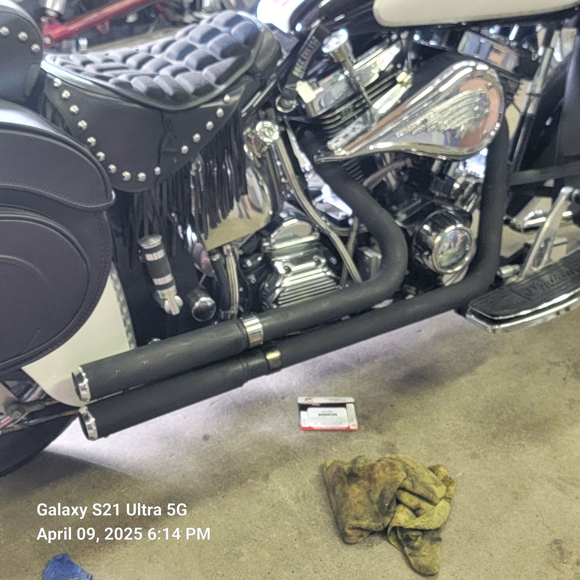 A motorcycle is parked in a garage next to a galaxy s21 ultra 5g.