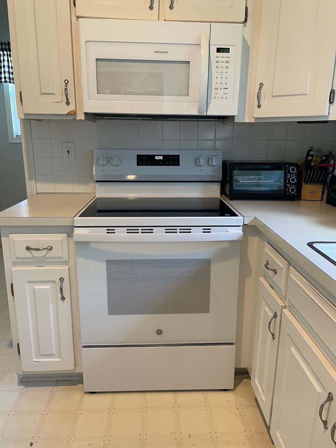White kitchen with stove, microwave, and light wood cabinets