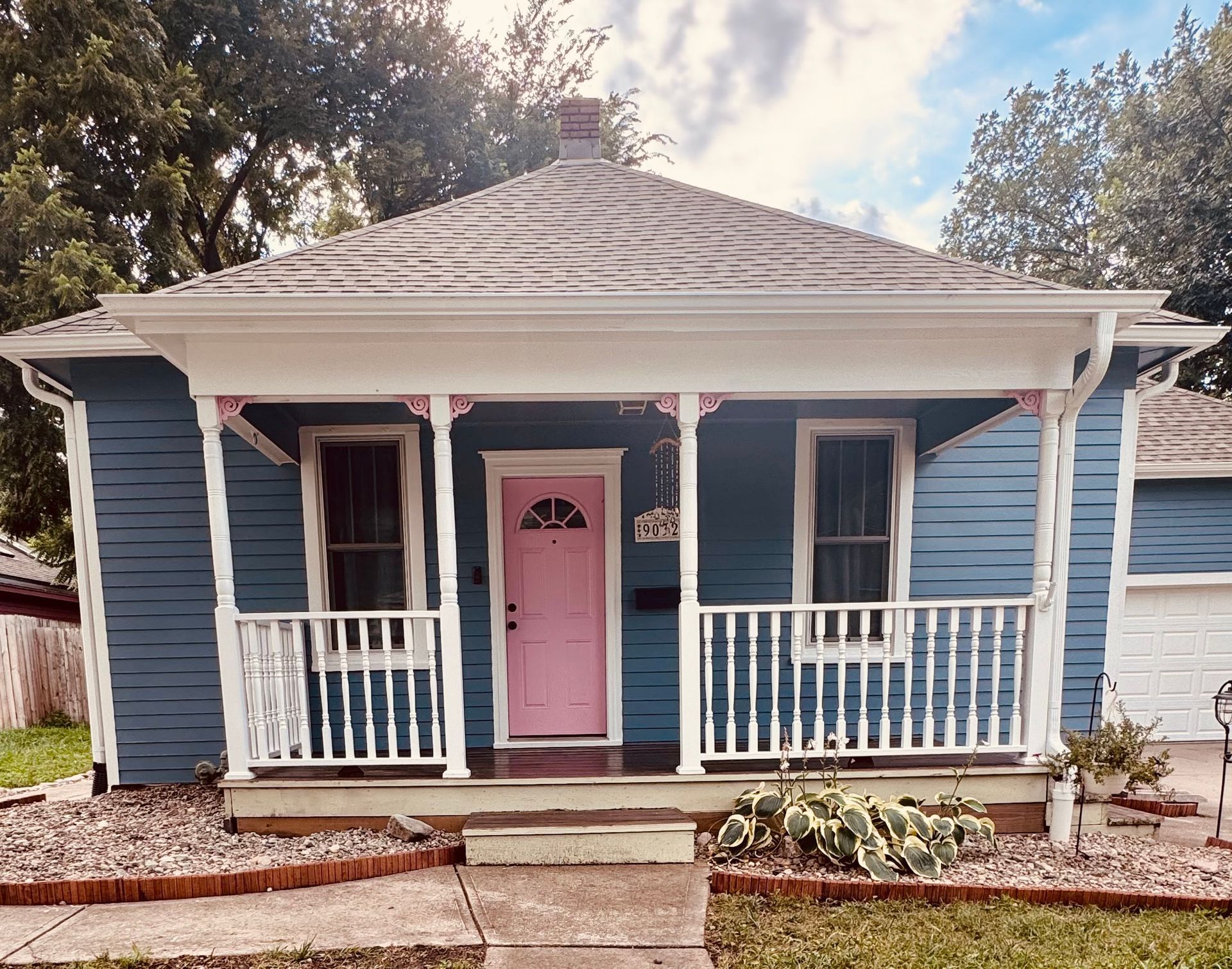 a picture of a blue house with white porch and pink door