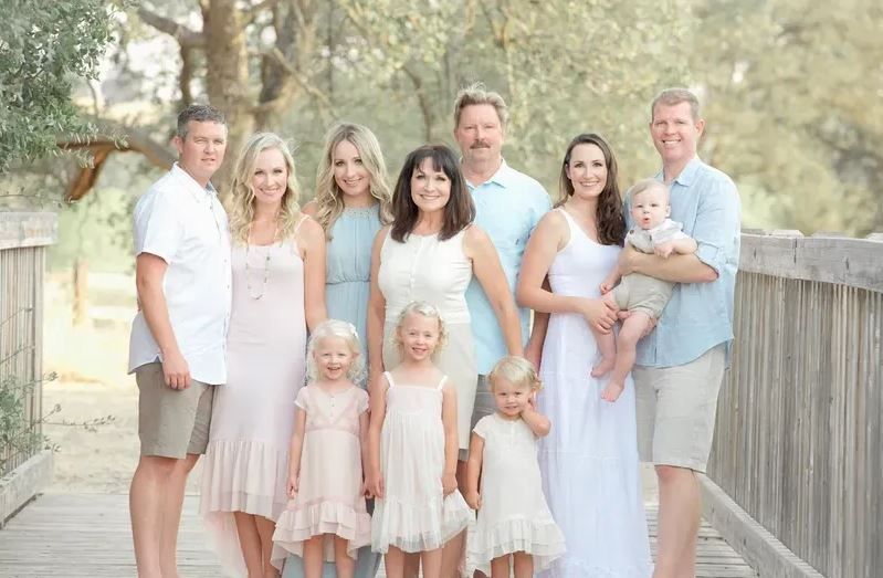 A large family is posing for a picture on a wooden bridge.