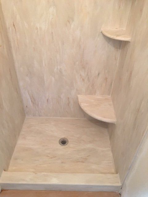 A shower stall with shelves and a drain in a bathroom.