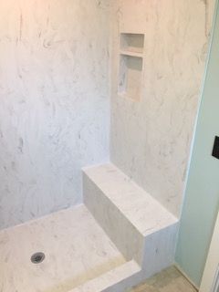 A bathroom with a shower and a bench in it.