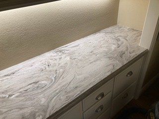 A kitchen counter with a marble counter top and white cabinets.