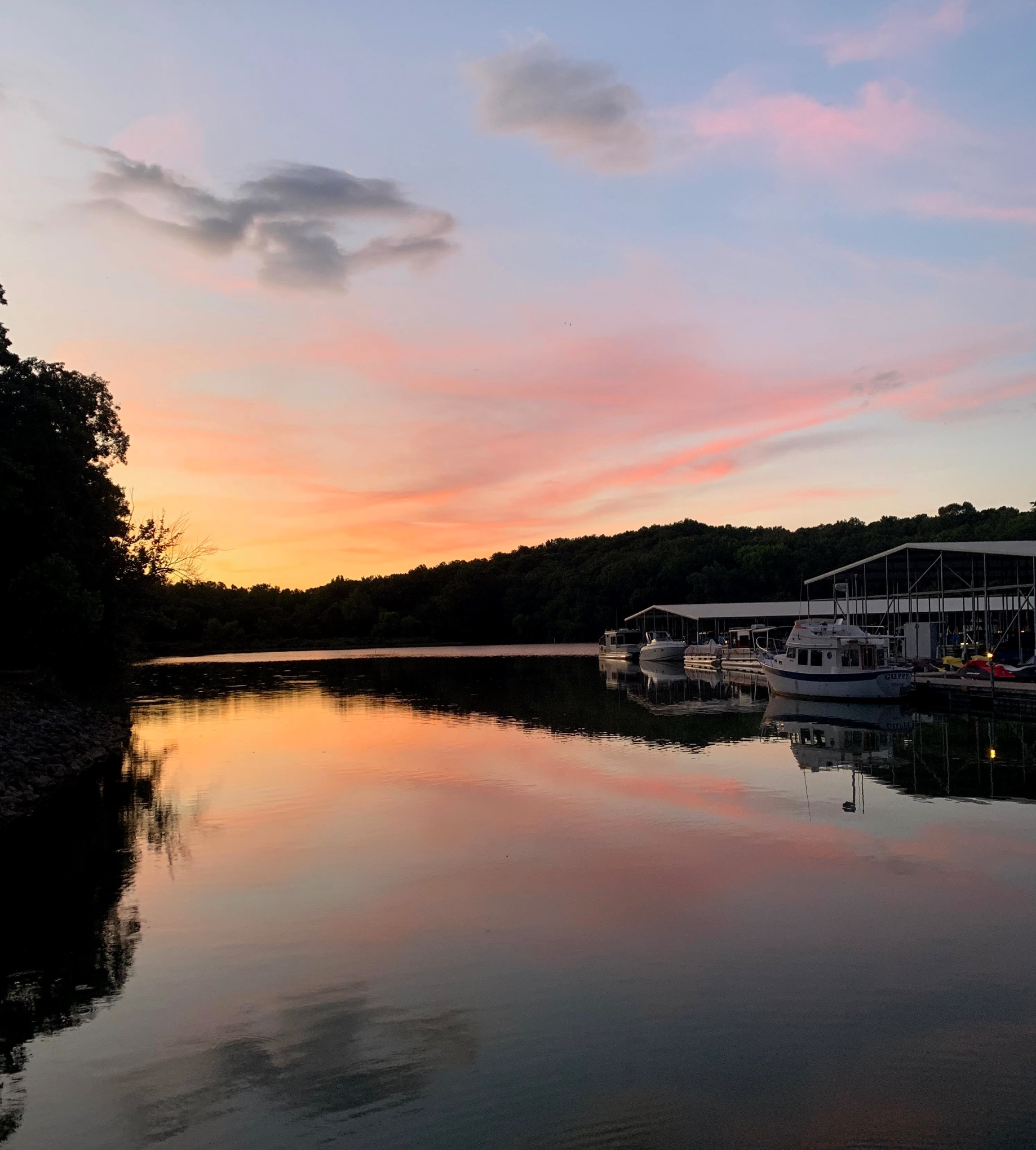 A sunset over a lake with boats docked in the water