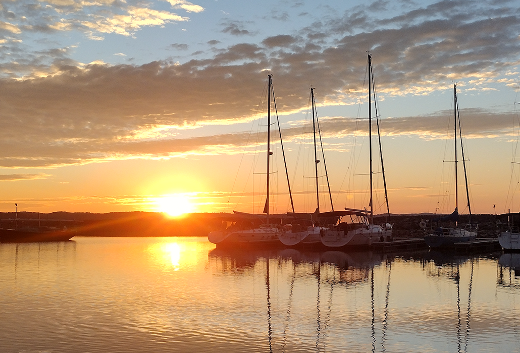 Boats are docked in a harbor at sunset