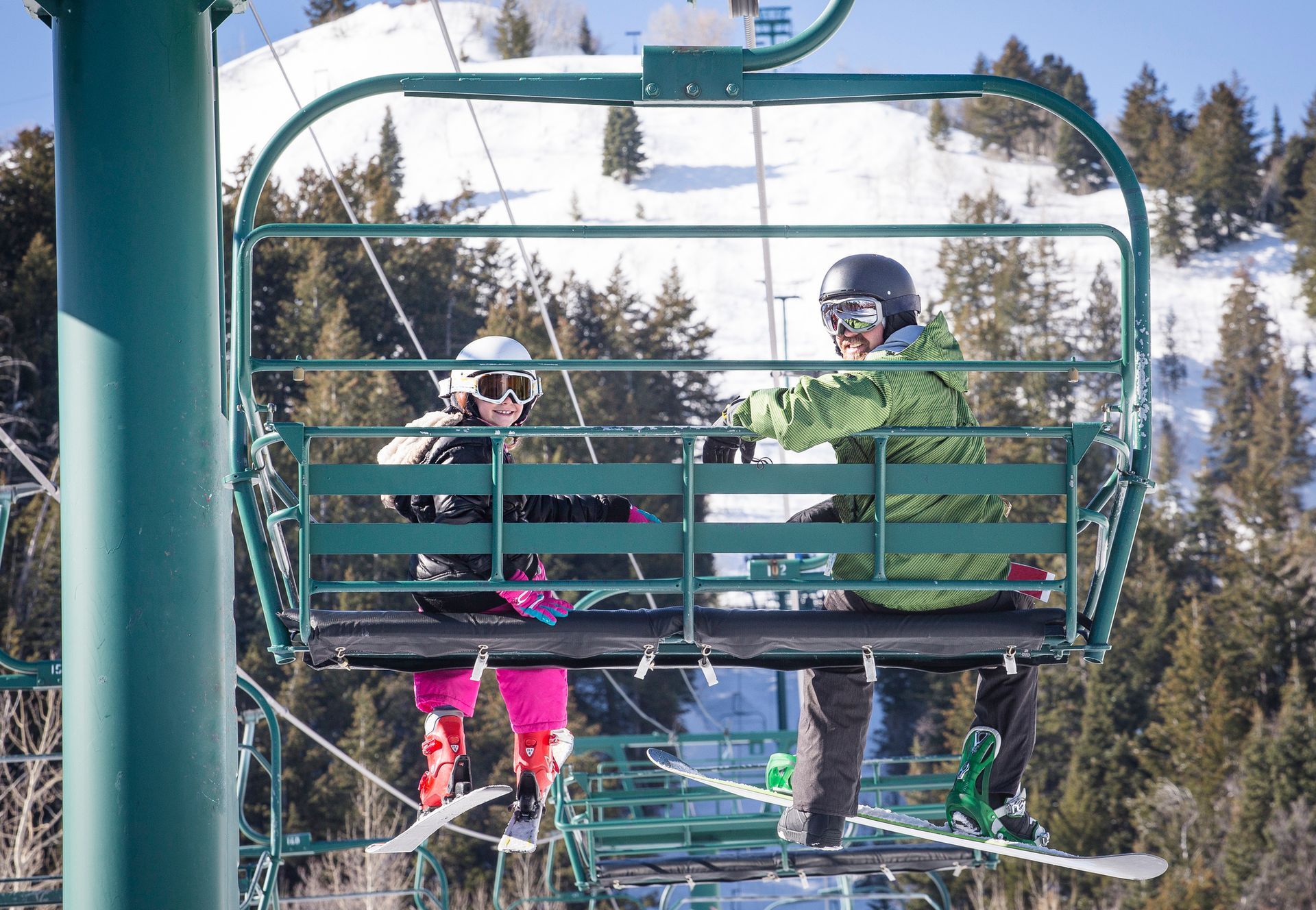 Two people are riding a ski lift in the mountains.