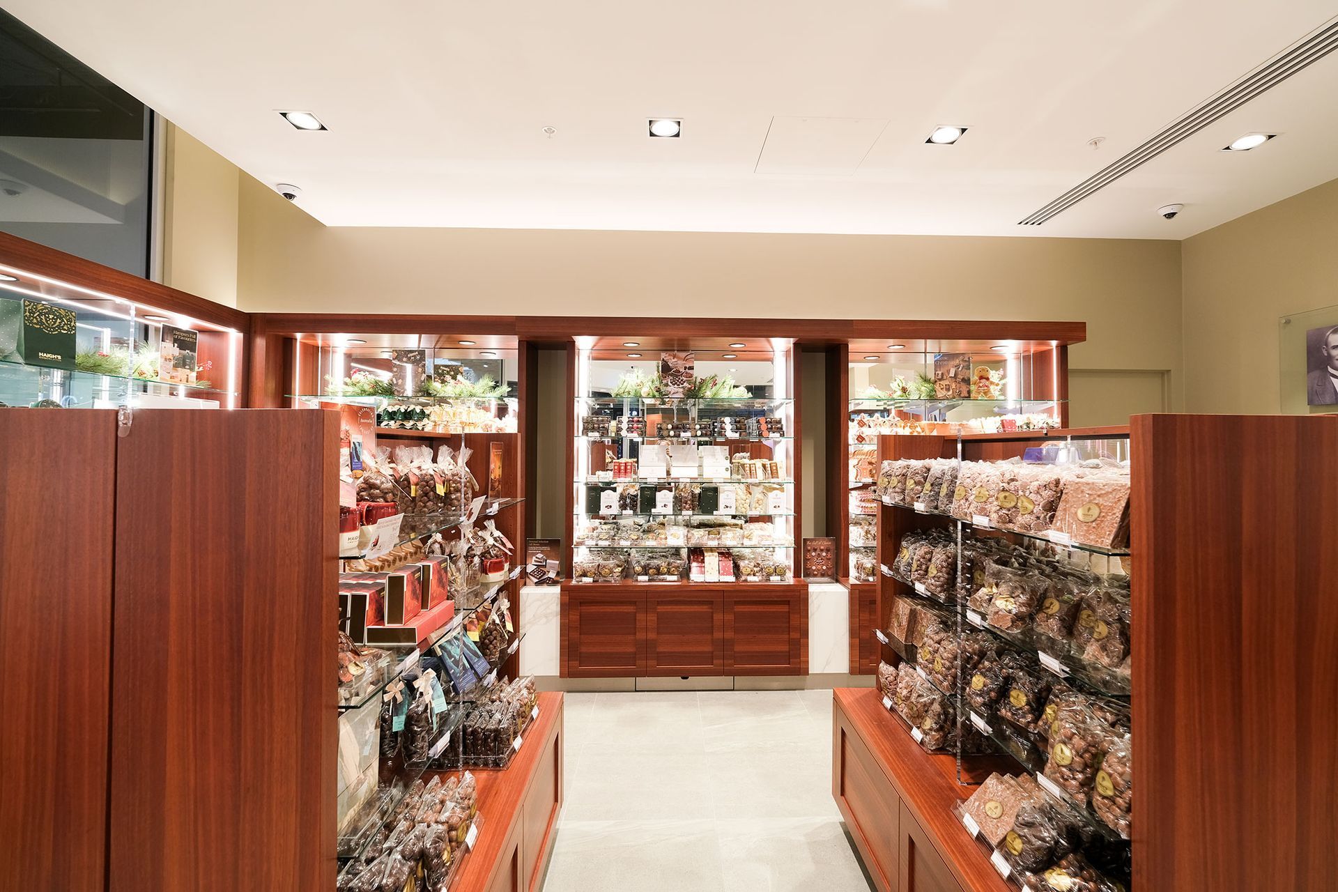 Inside a store, shelves stocked with products, wooden fixtures, recessed lighting.