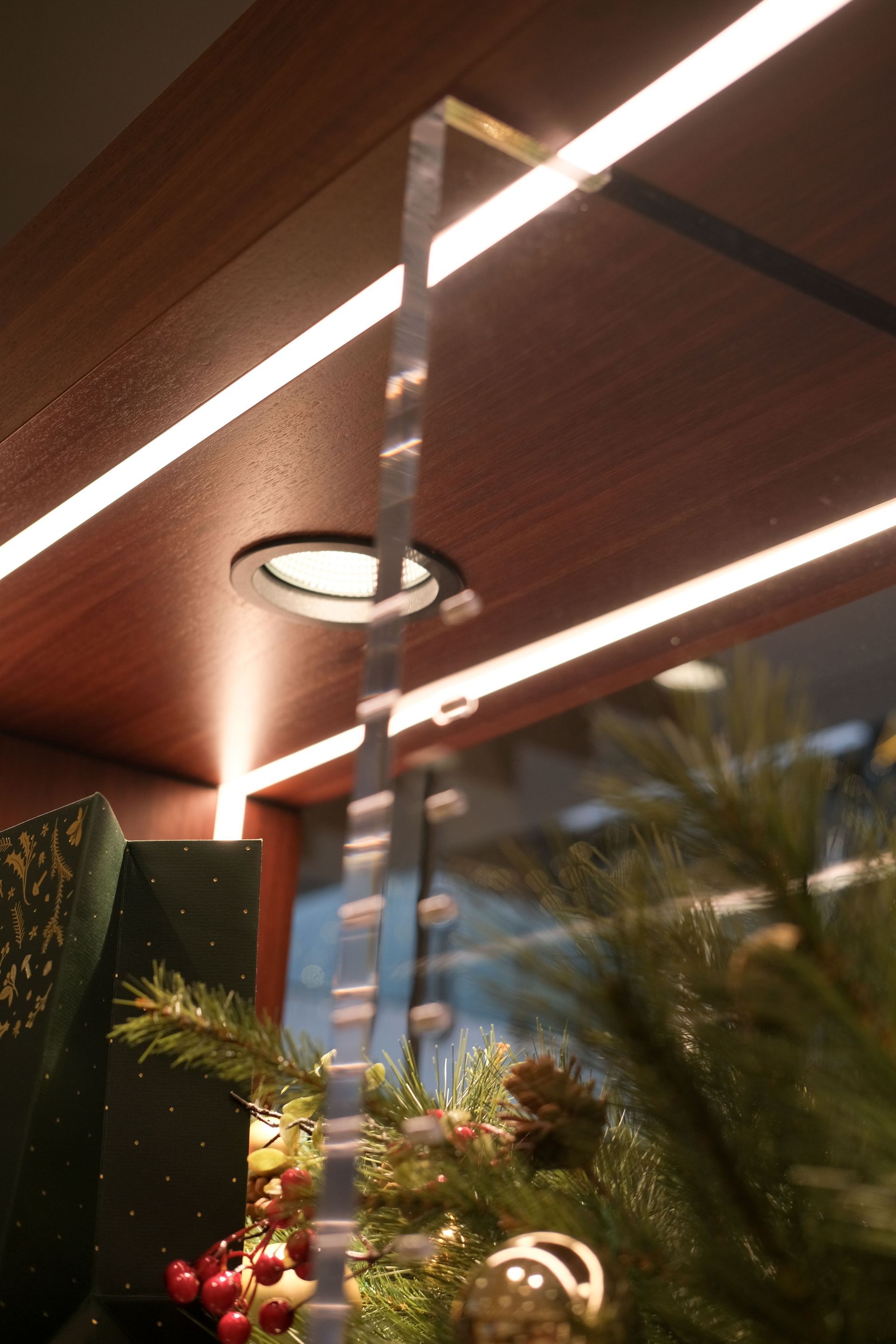 Bright overhead lighting illuminates dark wood shelving, with a decorative hanging chain and Christmas greenery in view.