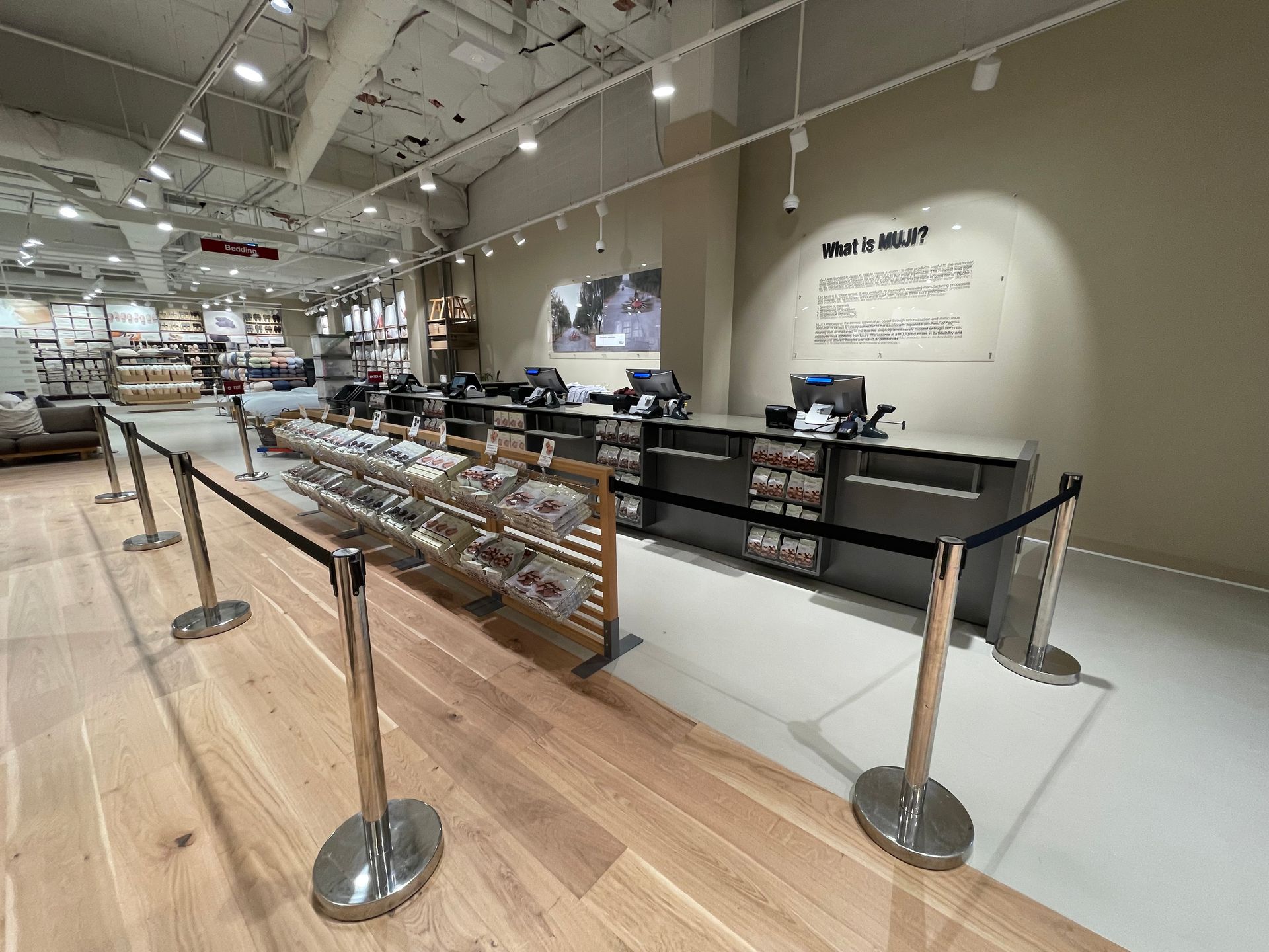 Checkout area in a store with wooden floor, products displayed, and a sign on the wall.