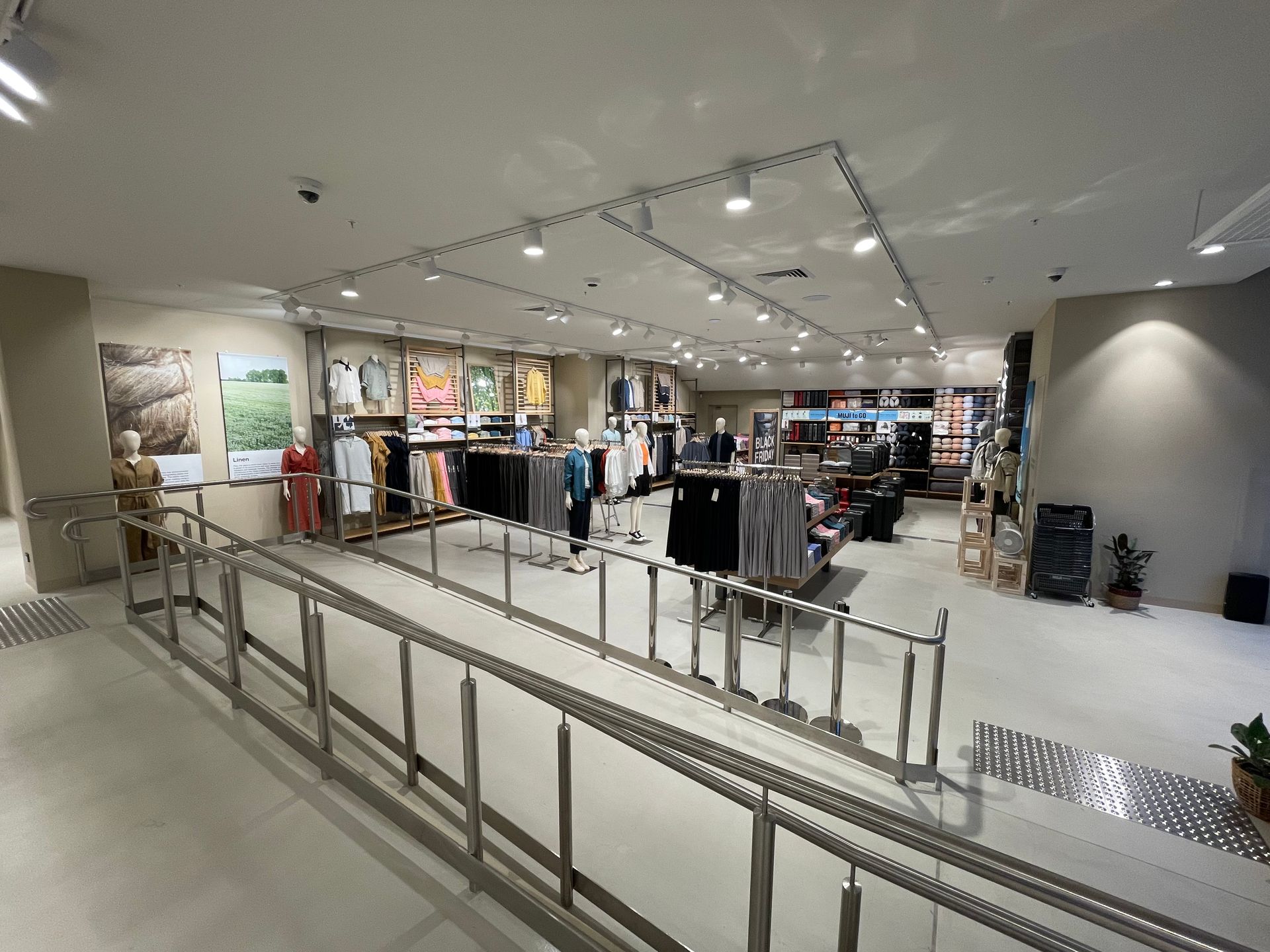Clothing store interior with accessible ramp, clothing racks, and mannequins.