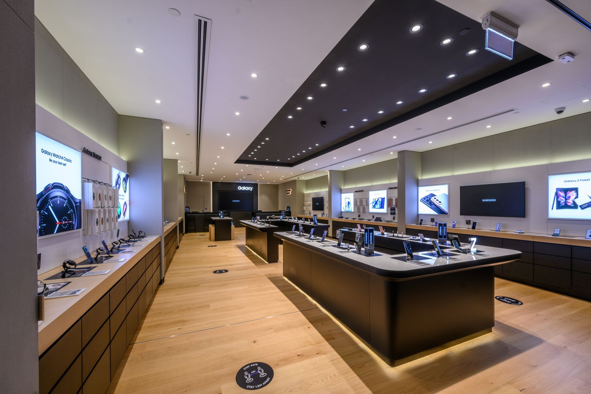 Interior of a modern electronics store with display tables and illuminated product displays.